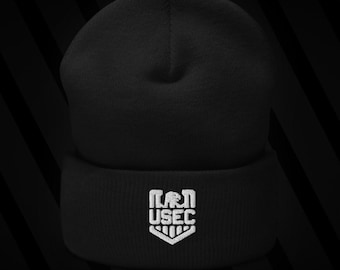 May include: Black beanie hat with a white embroidered USEC logo on the folded brim. The beanie is made of a soft, knitted material. The USEC logo is a stylized emblem.