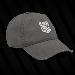 May include: Gray distressed baseball cap with the white embroidered text "USEC" in a shield design. The cap has a curved brim and a worn, vintage look, with distressed edges.