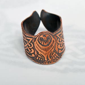 May include: A copper ring featuring an owl design. The owl is centrally positioned on the ring and is encircled by a Celtic knot pattern.