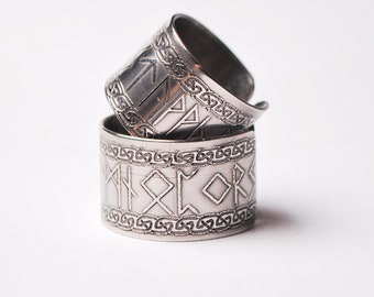 May include: Two silver rings with intricate designs. The rings are engraved with Norse runes and Celtic knotwork.