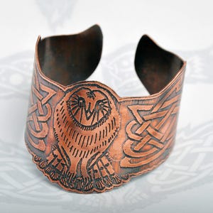 May include: Copper cuff bracelet featuring an embossed owl design. The wide bracelet has Celtic knotwork on either side of the owl. The metal has a dark, aged finish. A unique piece of jewelry.