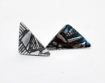 May include: A pair of silver triangle earrings with a textured surface.