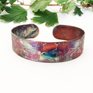 Copper flying magpies cuff with decorative, spiral pattern, multicoloured shiny, detailed bracelet with symmetrical winged birds motif