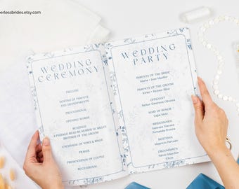 Puede incluir: Un folleto de programa de ceremonia y recepción de boda con un diseño floral azul. El folleto está abierto para mostrar el orden de los eventos de la ceremonia y los nombres de los miembros de la fiesta de bodas. El texto de la portada dice "Ceremonia de boda" y "Fiesta de boda".