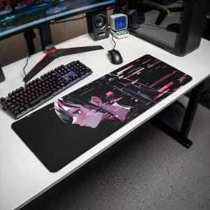 Może przedstawiać: Prostokątna podkładka na biurko z czarnym tłem i profilem postaci w stylu anime w odcieniach czerni, bieli i różu. Projekt zawiera cyfrowe efekty glitch oraz geometryczne różowe akcenty na całej powierzchni podkładki.