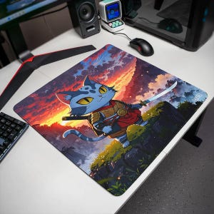 Peut inclure: Un tapis de bureau carré présentant une illustration colorée d'un chat bleu vêtu d'une armure de samouraï, tenant un katana. L'arrière-plan représente un coucher de soleil vibrant avec des nuages orange et violets sur un paysage rocheux.