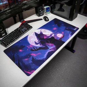 May include: A rectangular desk mat featuring a vibrant digital illustration of a fox-like character with long hair against a large full moon. The scene is rendered in deep shades of blue and purple with glowing pink accents and silhouettes of trees.
