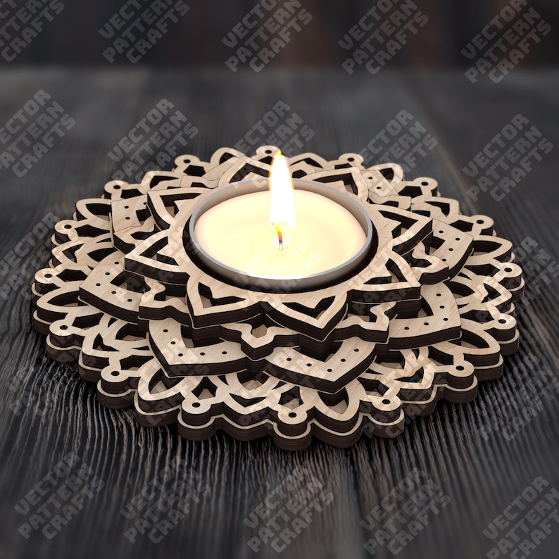 May include: A wooden candle holder with a floral design. The candle holder has a circular shape with layered, laser-cut patterns. A lit tea light candle sits in the center, casting a warm glow. The background is a dark wooden surface.