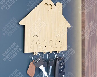 May include: Wooden house-shaped key holder with cutouts of a family of four. The key holder has a heart cutout at the top and five key hooks. There are five keys hanging from the hooks, including a car key.