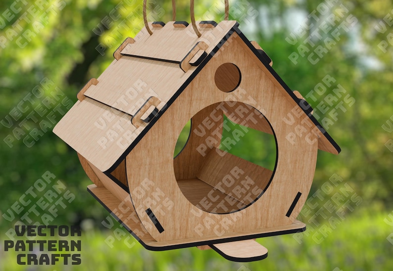 Op de afbeelding: Een houten vogelvoederhuisje in de vorm van een huis met een ronde opening waar vogels toegang hebben tot het voedsel. De voederbak is ontworpen om aan een haak of tak te worden gehangen.