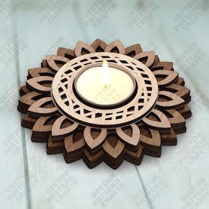 May include: A wooden candle holder with a sunflower design. The holder has a circular center with a geometric pattern, holding a lit candle. The base is made of layered wooden petals. The candle flame is bright.