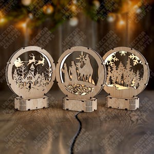 May include: Three wooden Christmas ornaments with circular frames and intricate cut-out designs. One features a church and reindeer, another the nativity scene, and the third a snowy forest. Each sits on a rectangular base.