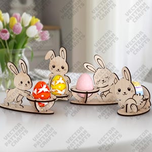 May include: Wooden Easter bunny decorations holding decorative eggs. The bunnies are laser cut and have a natural wood finish. The eggs are painted in various colors and patterns, including red, yellow, and pink.