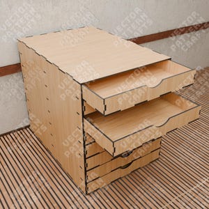 Op de afbeelding: Een houten organizer met vijf laden, elk met een zwarte rand. De bovenste lade is open, waardoor de lege binnenkant zichtbaar is. De organizer is gemaakt van licht hout en heeft een natuurlijke afwerking.