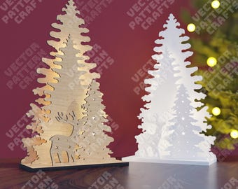 May include: Two wooden Christmas tree decorations with a deer silhouette in the center. The tree on the left is natural wood with a warm glow, while the tree on the right is white with a white glow. Both trees have stars cut out of them.