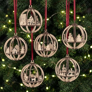 Peut inclure: Six décorations sphériques en bois présentant des scènes de fête découpées au laser, notamment des maisons, des sapins de Noël, des rennes et des cadeaux. Chaque ornement est en bois clair aux bords sombres et suspendu par un ruban de satin rouge.