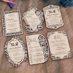May include: Laser-cut wooden wedding invitations in various shapes, including rectangular, oval, and floral designs. Each invitation features intricate cut-out patterns and personalized text with names, dates, and times. The invitations are light brown in color.