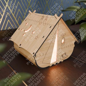 May include: A wooden camping tent night light with a moon, stars, and a lantern design. The tent has a light inside that shines through the opening.