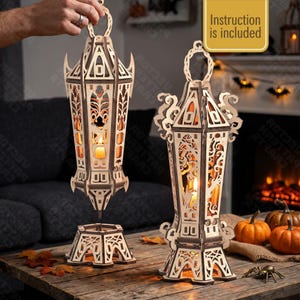 May include: Two laser-cut wooden lanterns with intricate gothic-style patterns and cutouts. One lantern is suspended in the air above its base, while the other stands upright on a wooden surface. Both feature warm internal lighting and a hanging loop.