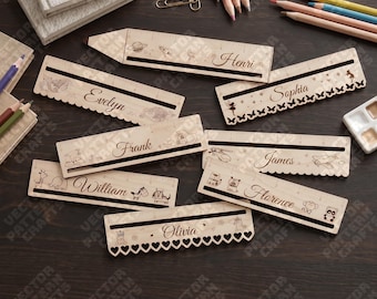 May include: A collection of light-colored wooden rulers featuring engraved names including Henri, Evelyn, Sophia, Frank, James, William, Florence, and Olivia. Each ruler displays unique etched illustrations such as space motifs, butterflies, vehicles, animals, and hearts, along with integrated measurement markings.