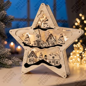 May include: A star-shaped wooden light display featuring a multi-layered winter village scene. The design includes silhouettes of houses, a church, pine trees, a deer, and a snowman, all illuminated from within to create a warm, glowing effect.