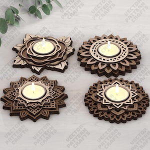 May include: Four wooden candle holders with lit candles. Each holder has a unique floral or geometric design, with a natural wood finish. The candle holders are arranged on a light-colored surface.