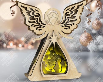 May include: A wooden angel Christmas decoration with layered wings and a star. The angel features a cutout design with a nativity scene illuminated inside. The angel is made of light-colored wood and is a festive holiday decoration.