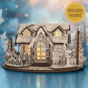 May include: A laser-cut wooden model of a house with a snow-covered roof, featuring a Santa Claus figure, a sleigh, two pine trees, and a mailbox labeled Letters to Santa. The house has a number 25 on the gable and includes an instruction included badge.