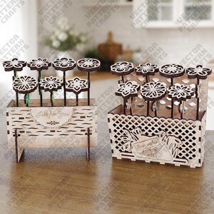 May include: Two wooden flower arrangements. One is a rectangular box with the text "Just for You". The other is a basket with the text "Best wishes". Both contain laser-cut wooden flowers with dark brown stems and white flower heads.