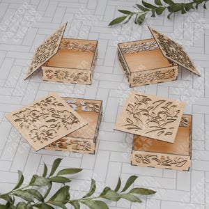May include: Four wooden boxes with intricate floral designs. The boxes are open and show the interior of the boxes. The boxes are made of light wood and have a natural finish.