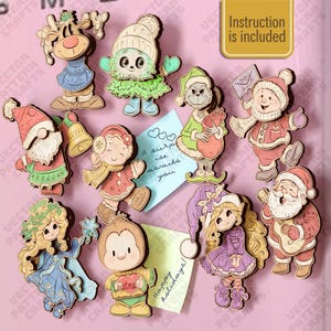Può includere: Una collezione di decorazioni natalizie in legno tagliate al laser raffiguranti vari personaggi tra cui una renna, un albero, uno gnomo, un bambino, una creatura verde, una fata e Babbo Natale. Il set include due foglietti con testo.