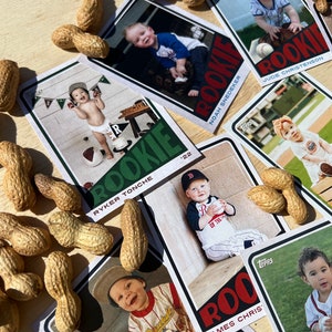Peut inclure: Cartes de rookie de baseball pour b&eacute;b&eacute;s avec des photos d'enfants en tenues de baseball. Les cartes sont dispos&eacute;es sur une surface en bois, entour&eacute;es de cacahu&egrave;tes. On peut lire le mot "ROOKIE" et l'ann&eacute;e "'22".