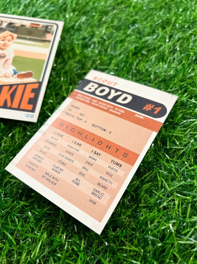 Peut inclure: Deux cartes de baseball vintage sur une surface verte. Une carte pr&eacute;sente un jeune enfant en uniforme de baseball avec le mot "ROOKIE" et le num&eacute;ro "22". L'autre carte est une carte "SCOUT BOYD #1" avec des points forts comme "I LOVE BATHS" et "YUMS PUFFS".