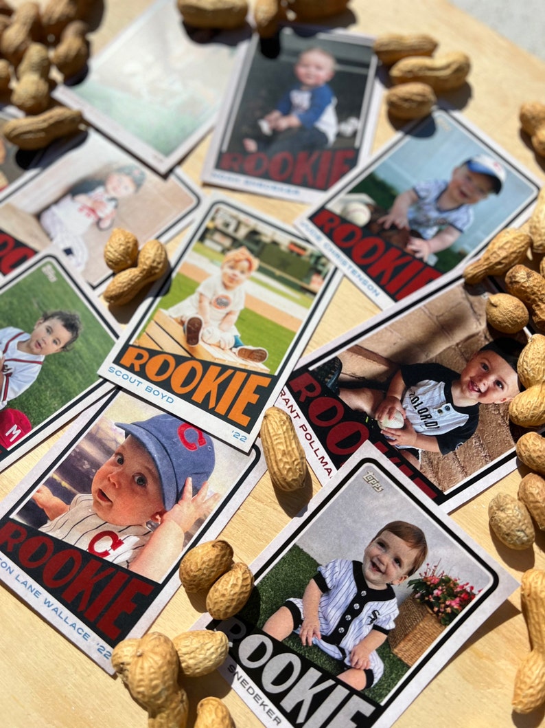 Peut inclure: Plusieurs cartes de baseball pour b&eacute;b&eacute;s avec le mot &laquo; ROOKIE &raquo; en &eacute;vidence. Les cartes pr&eacute;sentent des photos de b&eacute;b&eacute;s en tenues de baseball, entour&eacute;es de cacahu&egrave;tes. Les cartes ont un design vintage, avec l'ann&eacute;e '22 imprim&eacute;e sur certaines.