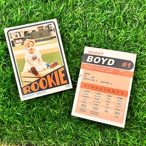 Peut inclure: Deux cartes de collection de style vintage sur de l'herbe verte. L'une pr&eacute;sente une photo de b&eacute;b&eacute; avec le mot "ROOKIE" et "SCOUT BOYD". L'autre carte r&eacute;pertorie les faits marquants et les statistiques du b&eacute;b&eacute;.