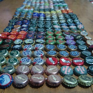 May include: A close-up of a colorful mosaic made from bottle caps. The mosaic is arranged in a rainbow pattern and features a variety of colors, including red, orange, yellow, green, blue, indigo, and violet. The bottle caps are arranged in rows and columns, creating a visually appealing design.