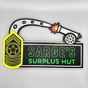 May include: A sign featuring a yellow and black military rank insignia and the text "SARGE'S SURPLUS HUT" in green on a black background. A cartoon cannon is above the text, with a white barrel and a red and yellow explosion.