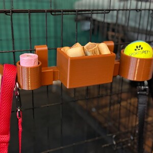 Heat-resistant PETG dog crate organiser with moveable hooks. Stores a tennis ball, poo bags, treats, and leads. Perfect for dog walkers and owners. Quick to attach without screws, it’s a tidy and practical crate accessory in brown or custom colours.