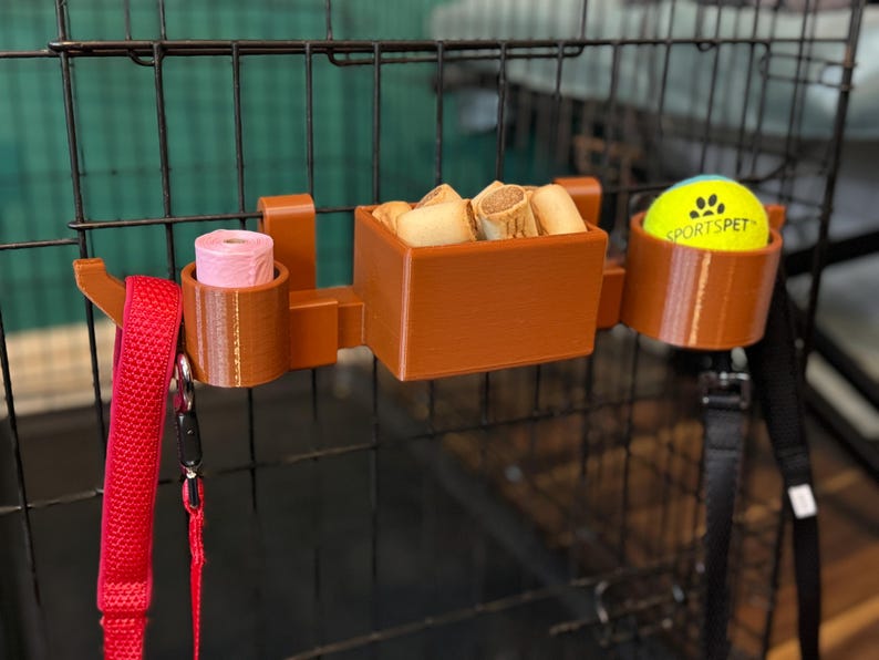 Heat-resistant PETG dog crate organiser with moveable hooks. Stores a tennis ball, poo bags, treats, and leads. Perfect for dog walkers and owners. Quick to attach without screws, it’s a tidy and practical crate accessory in brown or custom colours.