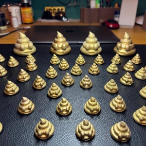 A mixture of 5cm and 2cm tall golden glittered poop emoji 3D prints rest on a black leather surface. All of the poops are smiling with eyes slightly protruding from their heads.