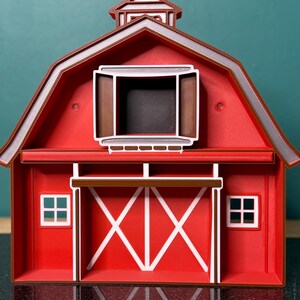 Puede incluir: Maqueta de granero rojo con detalles blancos, tejado marr&oacute;n y c&uacute;pula. Las puertas del granero son blancas con dise&ntilde;o de X. Dos peque&ntilde;as ventanas flanquean las puertas. La maqueta es una r&eacute;plica en miniatura de un granero cl&aacute;sico.