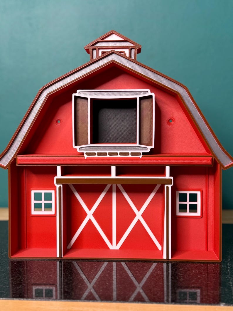 Puede incluir: Maqueta de granero rojo con detalles blancos, tejado marr&oacute;n y c&uacute;pula. Las puertas del granero son blancas con dise&ntilde;o de X. Dos peque&ntilde;as ventanas flanquean las puertas. La maqueta es una r&eacute;plica en miniatura de un granero cl&aacute;sico.