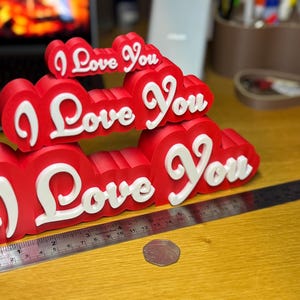 3D printed ‘I Love You’ signs in mini (8cm), regular (16cm), and giant (24cm) sizes. Ideal for Valentine’s Day gifts, romantic decor, anniversaries, or special occasions. Features bold red hearts with white protruding letters for a unique decoration.