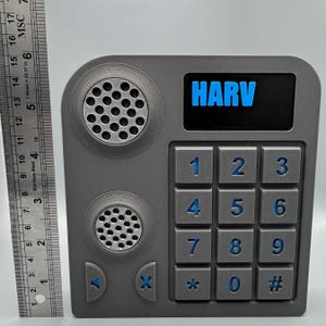 May include: A gray, rectangular device with a keypad, speakers, and the word "HARV" in blue. The keypad has numbers 0-9, an asterisk, and a pound sign. The device has two circular speaker grills and arrow buttons.