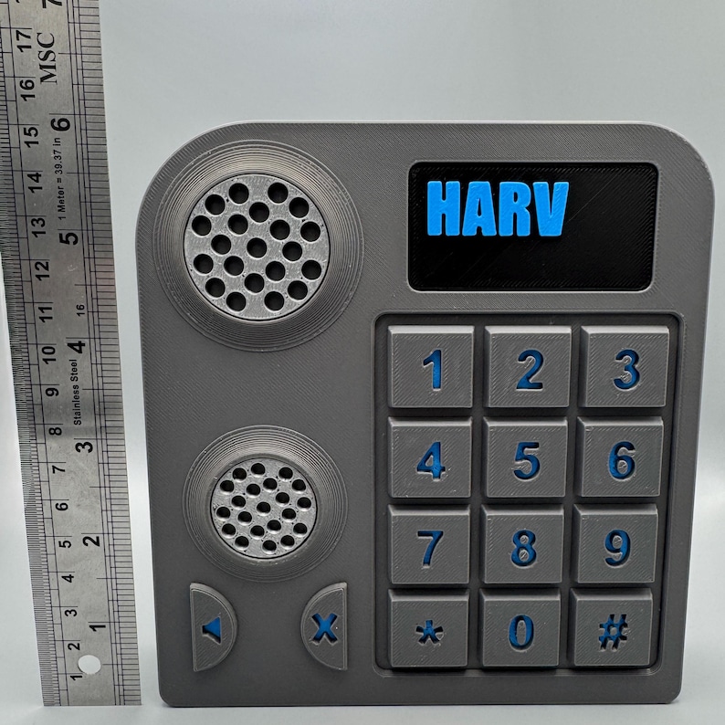 May include: A gray, rectangular device with a keypad, speakers, and the word "HARV" in blue. The keypad has numbers 0-9, an asterisk, and a pound sign. The device has two circular speaker grills and arrow buttons.