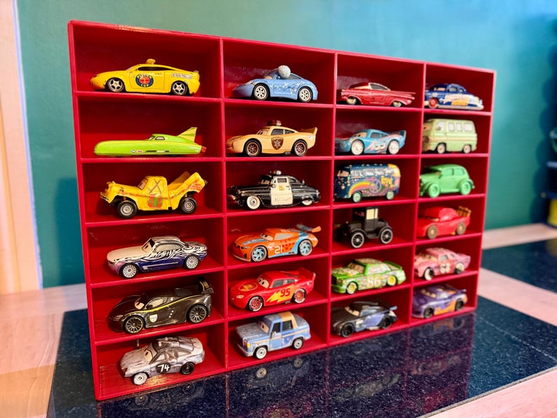 May include: A red display shelf filled with a collection of toy cars. The cars are various colors and styles, including a yellow taxi, a blue race car, and a green van. The shelf has multiple compartments.