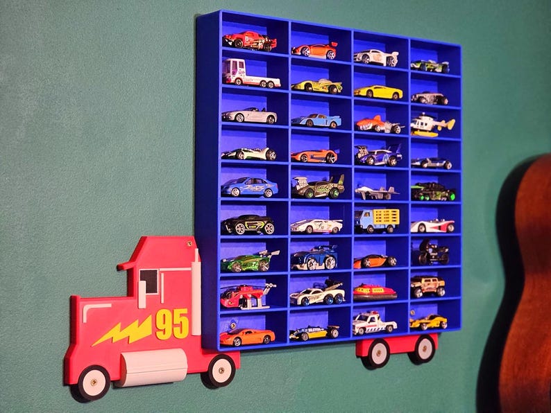 Blue toy car shelf inspired by Lightning McQueen, featuring 36-144 compartments for storing toy cars or Hot Wheels. A bold red truck design with yellow lightning bolt and the number 95 on the cab adds a fun, themed touch to any kid’s room