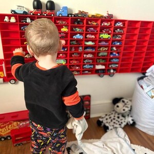 Child playing with a wall-mounted display inspired by Disney’s Mack from Cars, perfect for kids to showcase their car collections. The truck design adds a playful touch while providing organised storage for toy cars, making it both fun and functional