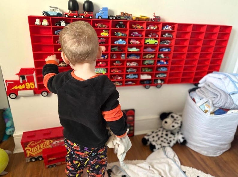 Child playing with a wall-mounted display inspired by Disney’s Mack from Cars, perfect for kids to showcase their car collections. The truck design adds a playful touch while providing organised storage for toy cars, making it both fun and functional