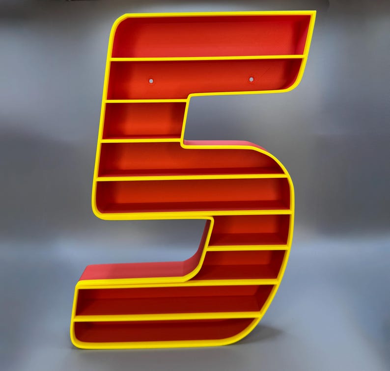 May include: A large, number-shaped shelf unit in the form of the number 5. The shelves are red with yellow trim. The unit is designed to be mounted on a wall and has pre-drilled holes for hanging. The overall design is modern and eye-catching.